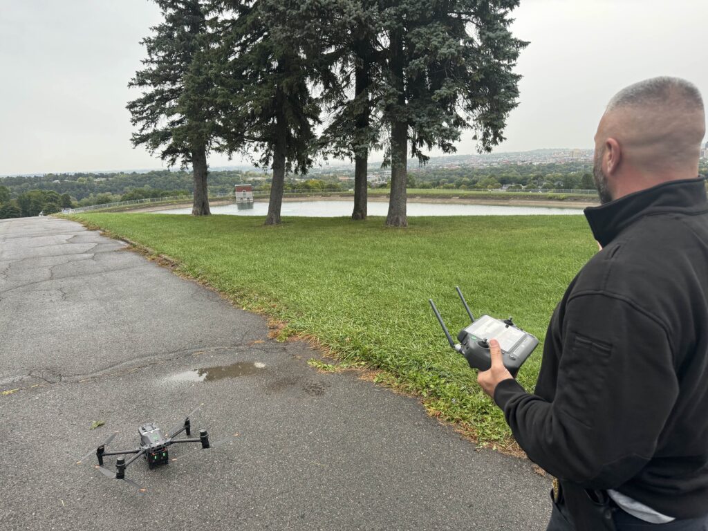 Officer of SPD deploying a drone on a grassy hill.