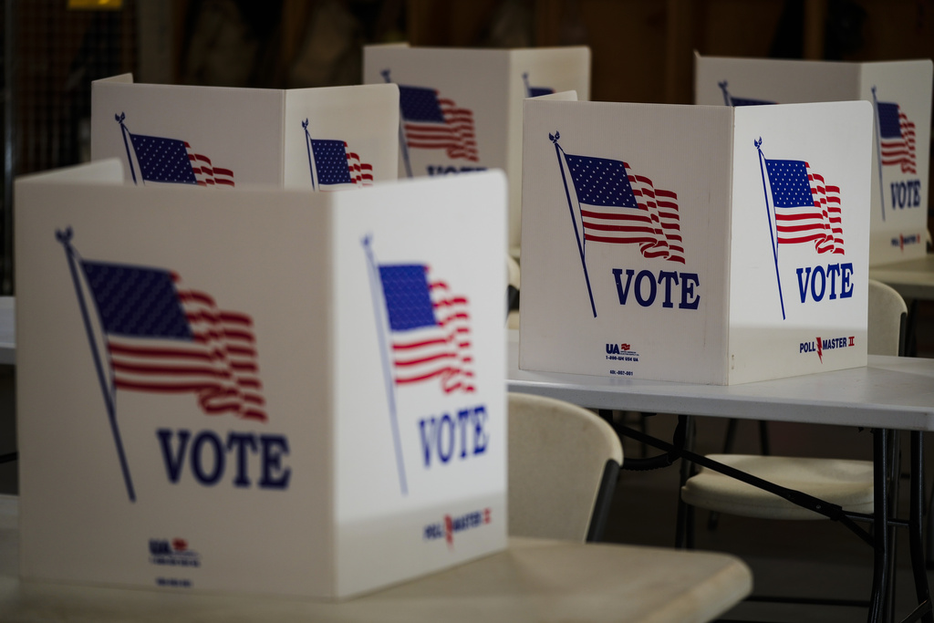 White plastic boxes with American Flag and the word "vote" on it. The boxes sit on tops of desks for voting purposes.