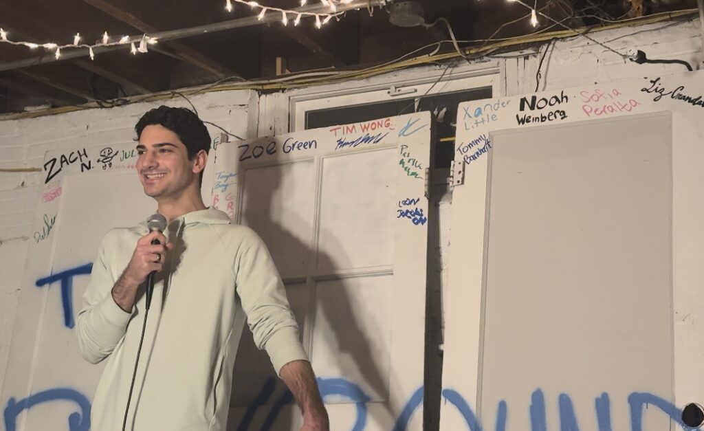 Zach Nemirovsky smiling on stage performing his set in front of the doors.