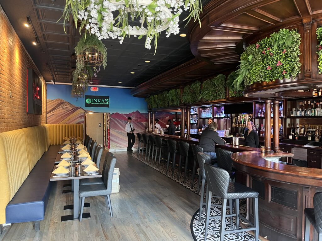 The interior of Inka's Peruvian restaurant in Syracuse that has a bar and table seating with plant decorations.