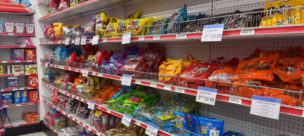 Three shelves of candy in a local grocery store, including chocolate candies.