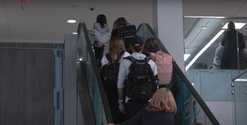 Syracuse passengers on escalator towards TSA