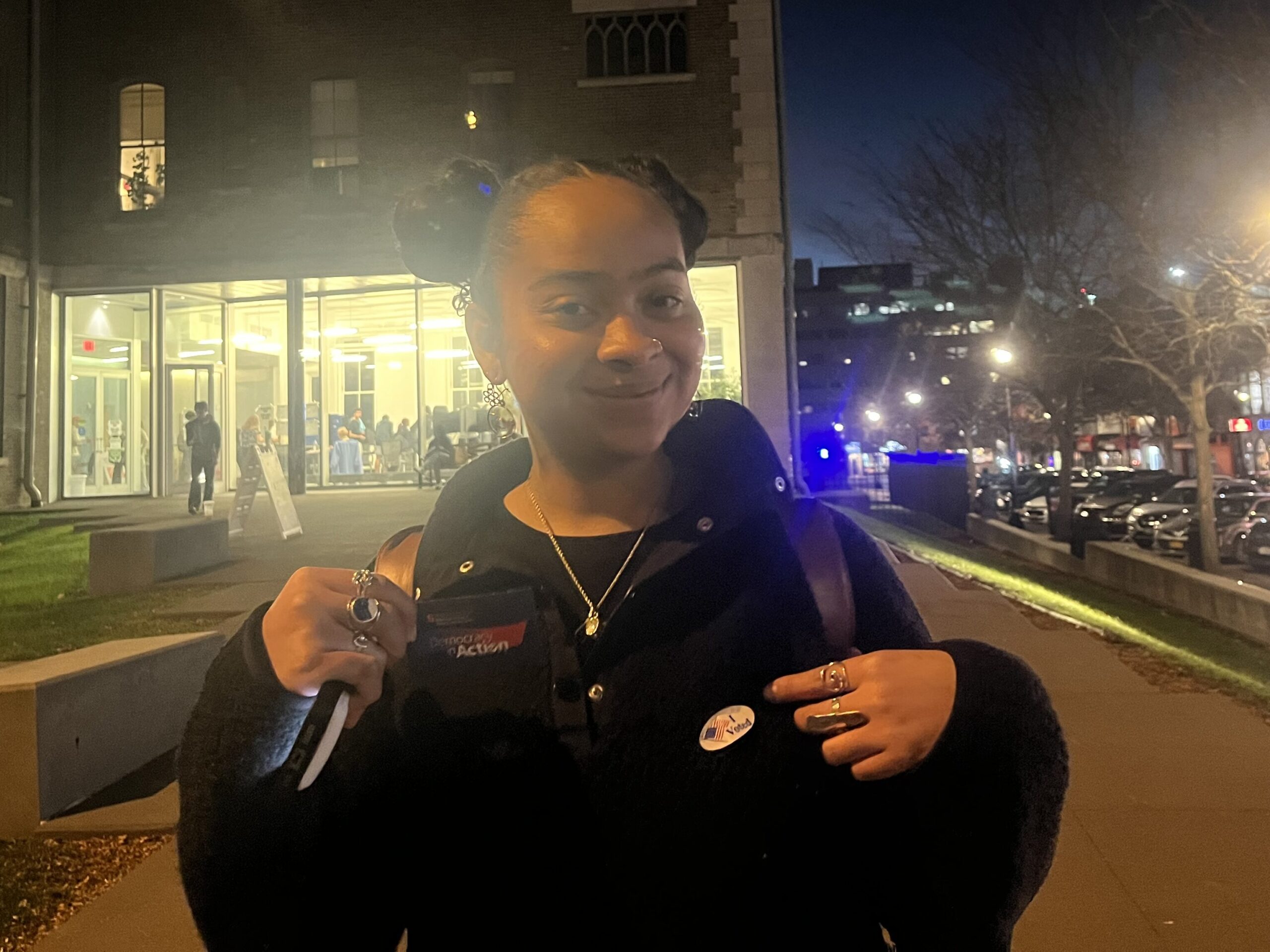 Savanna Capdeville wearing her "I voted" sticker in front of Huntington Hall