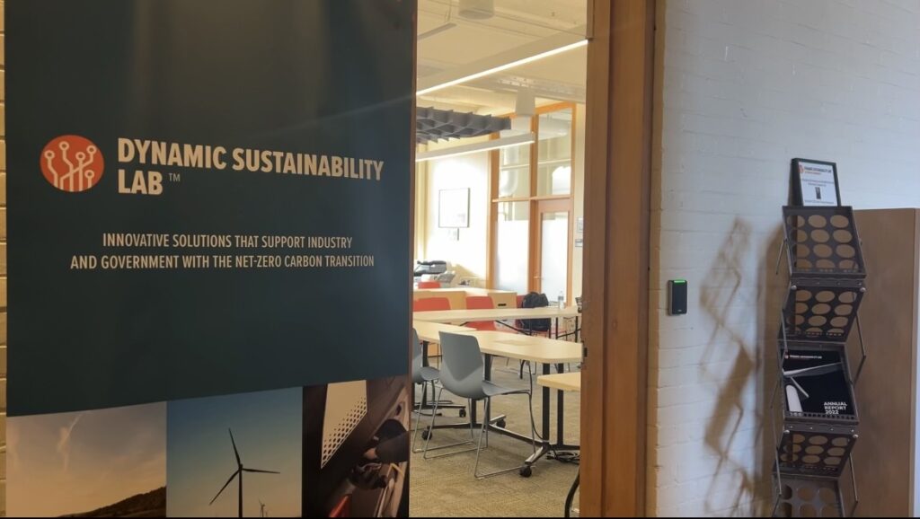 The entrance to lab space next to a poster for the Dynamic Sustainability Lab with desks and chairs.