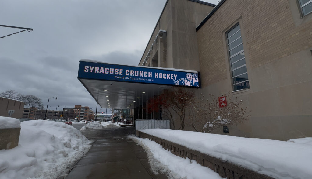 The side of an arena marquee, displaying "Syracuse Crunch Hockey" on the board