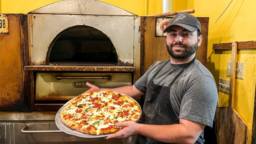 Owner Claudio Bueti Jr. shows off his favorite chicken pram pizza at Il Limone.