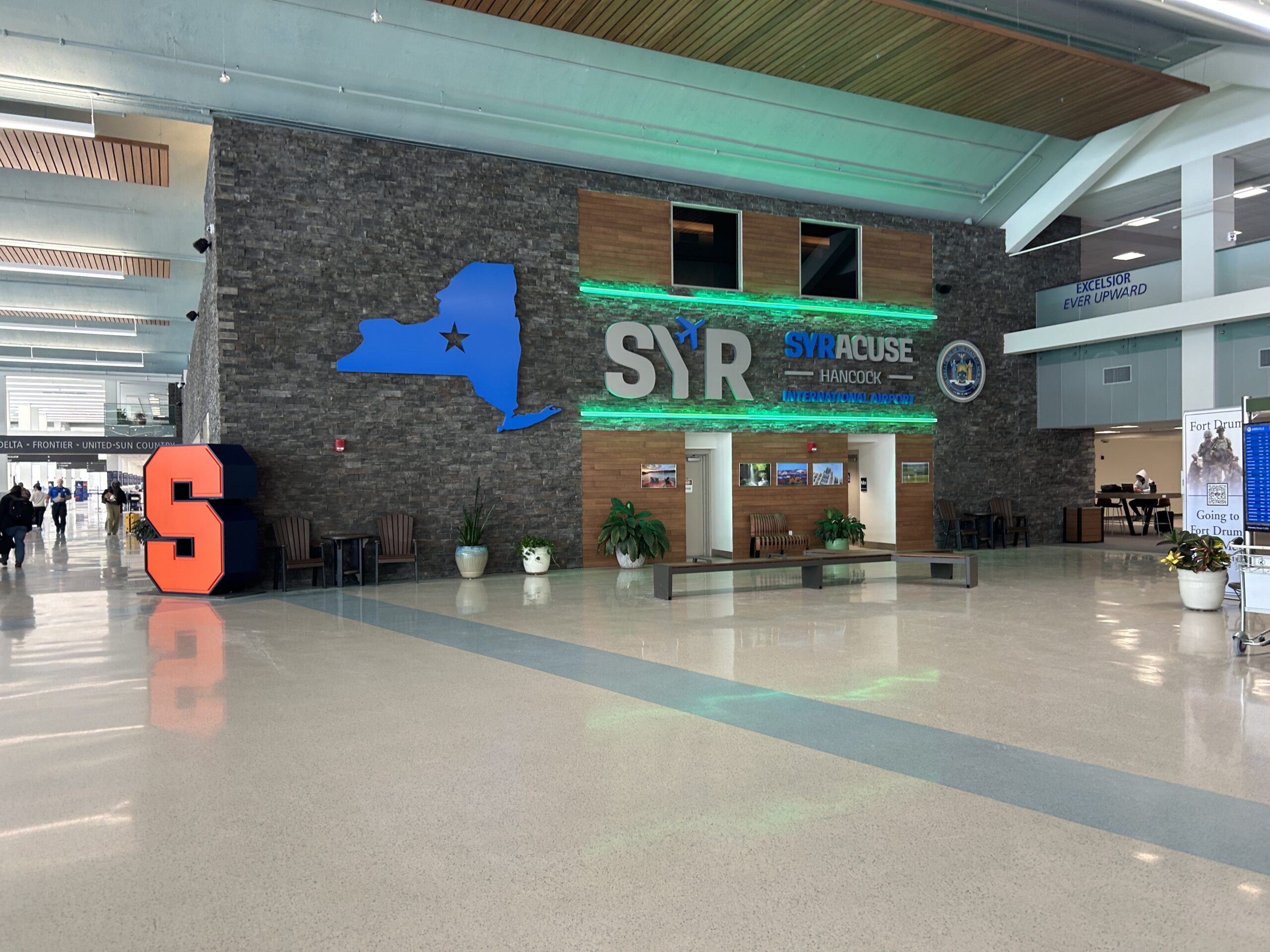 Interior of Syracuse Hancock International Airport. SYR logo is accompanied by a little airplane in the Y and a silhoutte of New York at the right of the SYR letters. Green leds are at the top and bottom of the logo.
