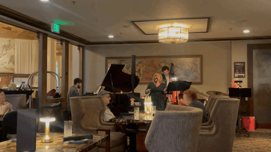 Woman in green dress sings in front of a piano and drums