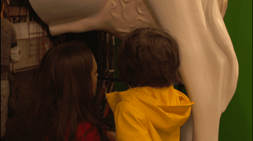 volunteer showing child a milking simulator