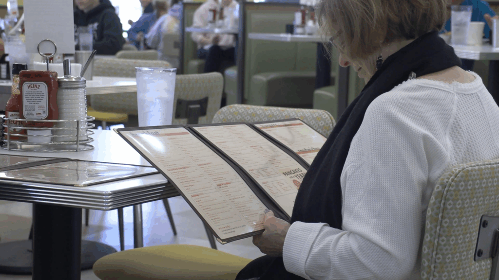 A visitor at The Daily Diner is looking over the menu before ordering on Opening Day.