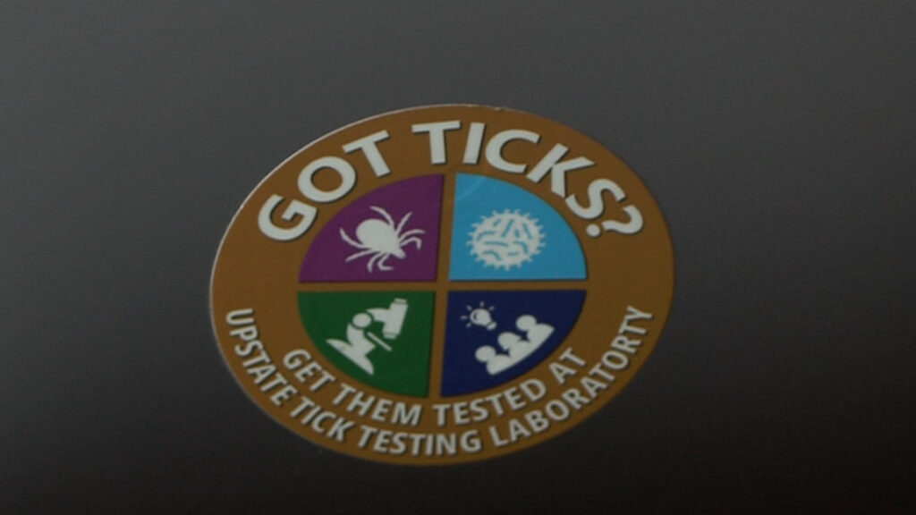 Sticker on Dr. Saravanan Thangamani reminding everyone to send tick that have bitten humans into the lab for testing.@ 2025 Geraldine Paglia