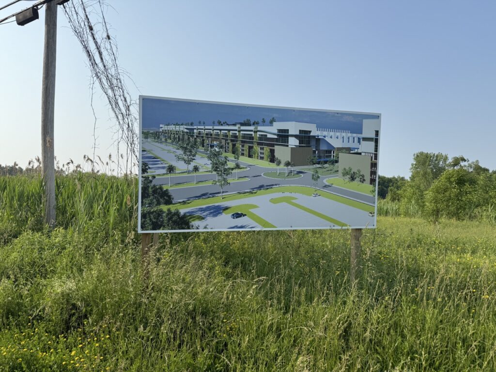 Sign showing a rendering of the future Micron chip plant standing in a grassy field in the town of Clay, New York.