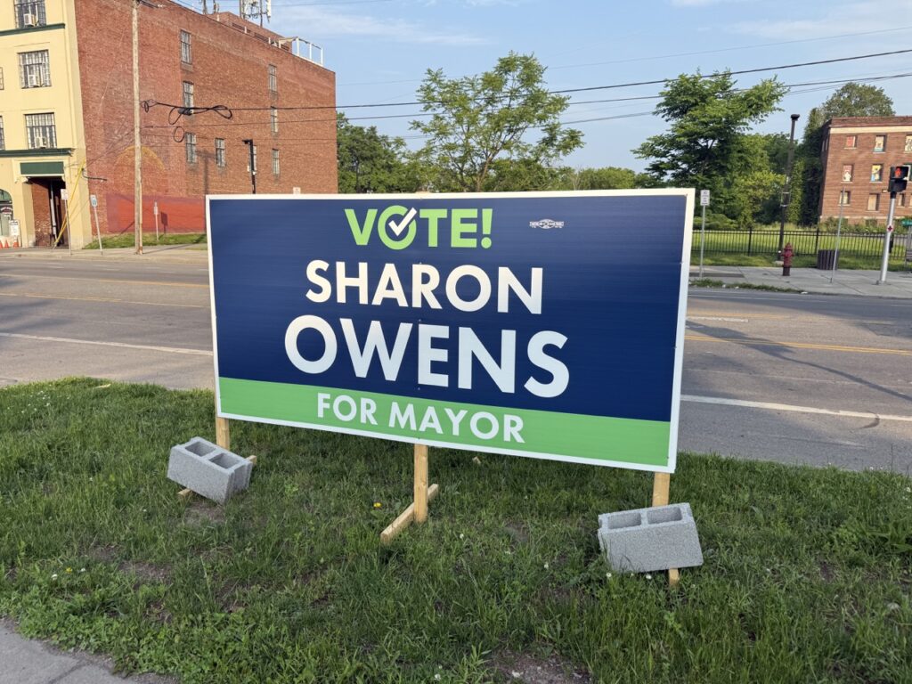 A campaign sign reading "Vote for Sharon Owens" is placed on a grassy patch beside a Syracuse sidewalk ahead of the upcoming Democratic primary.