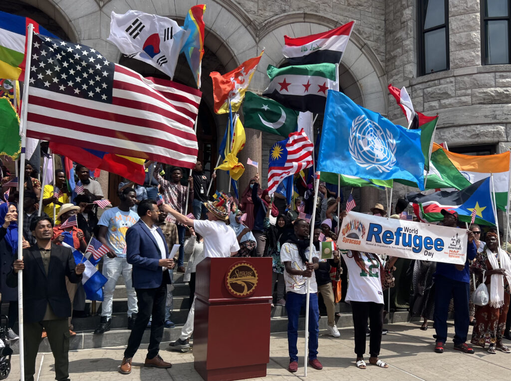 People holding different international flags in front of City Hall building