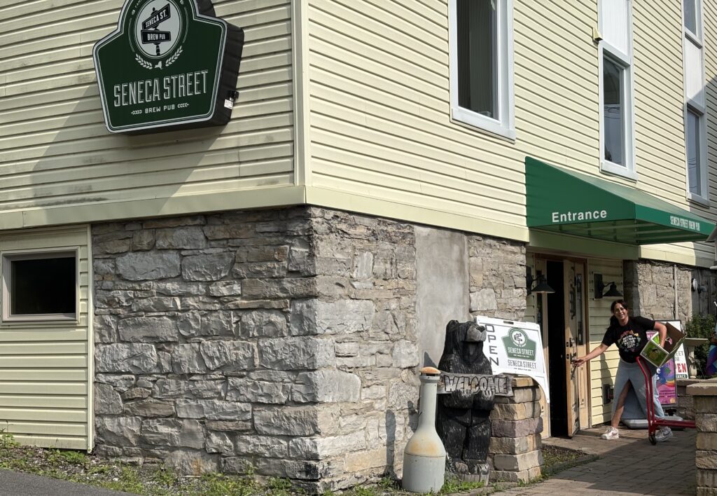 Pub owner Heidi Menikheim is setting up supplies for the Pride Festival, a labor of love she’s led for years, carefully laying out flags, coordinating food vendors, and prepping her bar’s outdoor space for a day of joy and inclusivity.