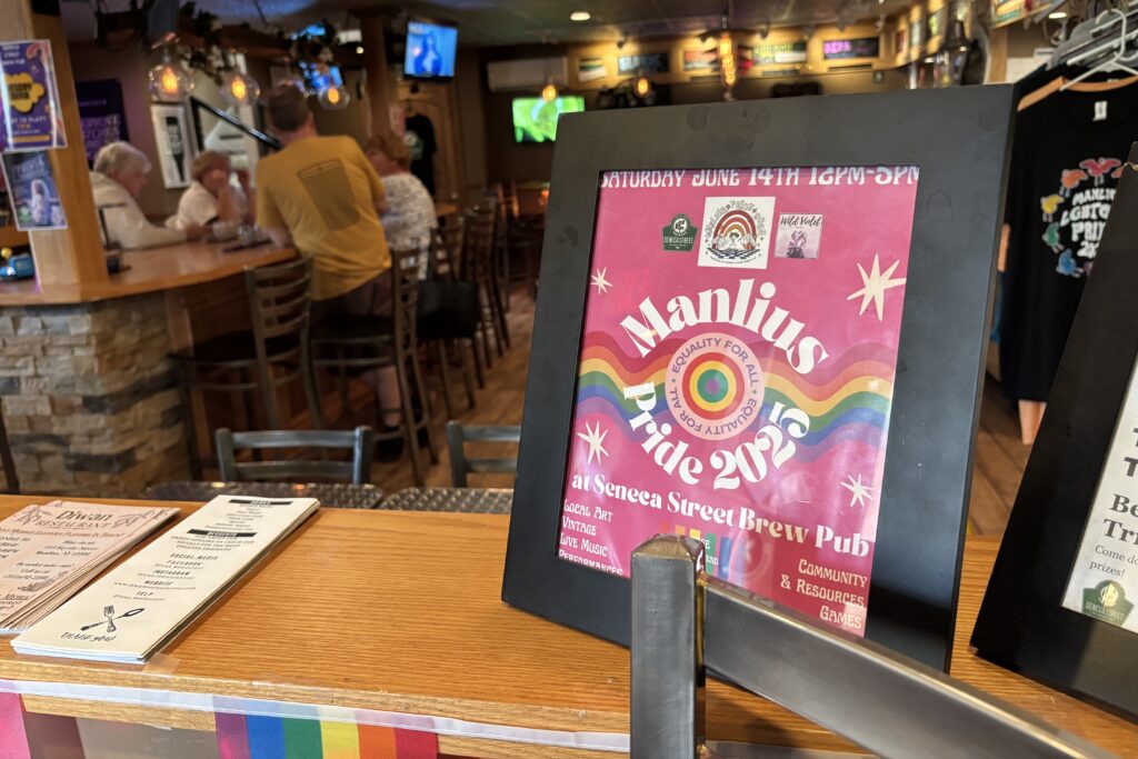 Manlius Pride signs overtake the Seneca Street Brew Pub as organizers get ready for the event, transforming the quiet street into a vibrant festival space.