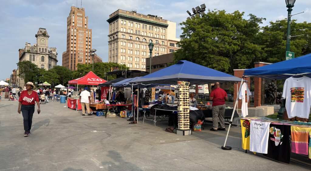 A community outreach table for Citizens in Action, featuring informational flyers, clipboards, and volunteers engaging with festival attendees.
