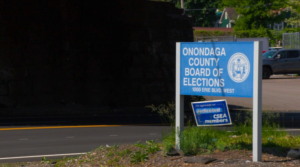 A sign marks the entrance to the Onondaga County Board of Elections office at 1000 Erie Blvd. West. Staff are preparing for the June 14 start of early voting. © 2025 Maria Wainscott