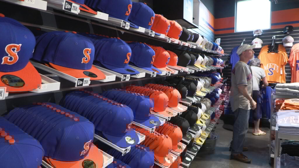 Rows of baseball hats hanging on a wall.