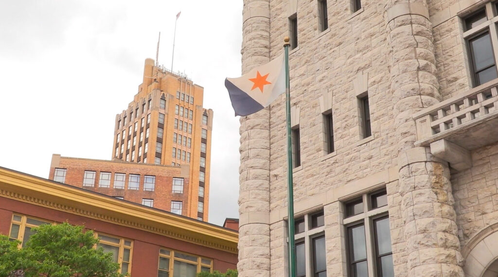 Syracuse City Hall is seen with the Syracuse city flag flying in front on Monday, June 2, 2025. City voters will head to the polls for early voting starting June 14. © 2025 Maria Wainscott