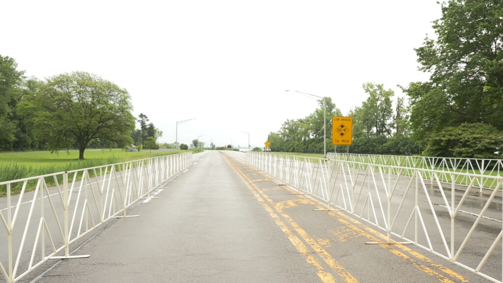The Onondaga Lake Parkway on a rainy day. White metal barriers are placed in the road to split it into two long sections.