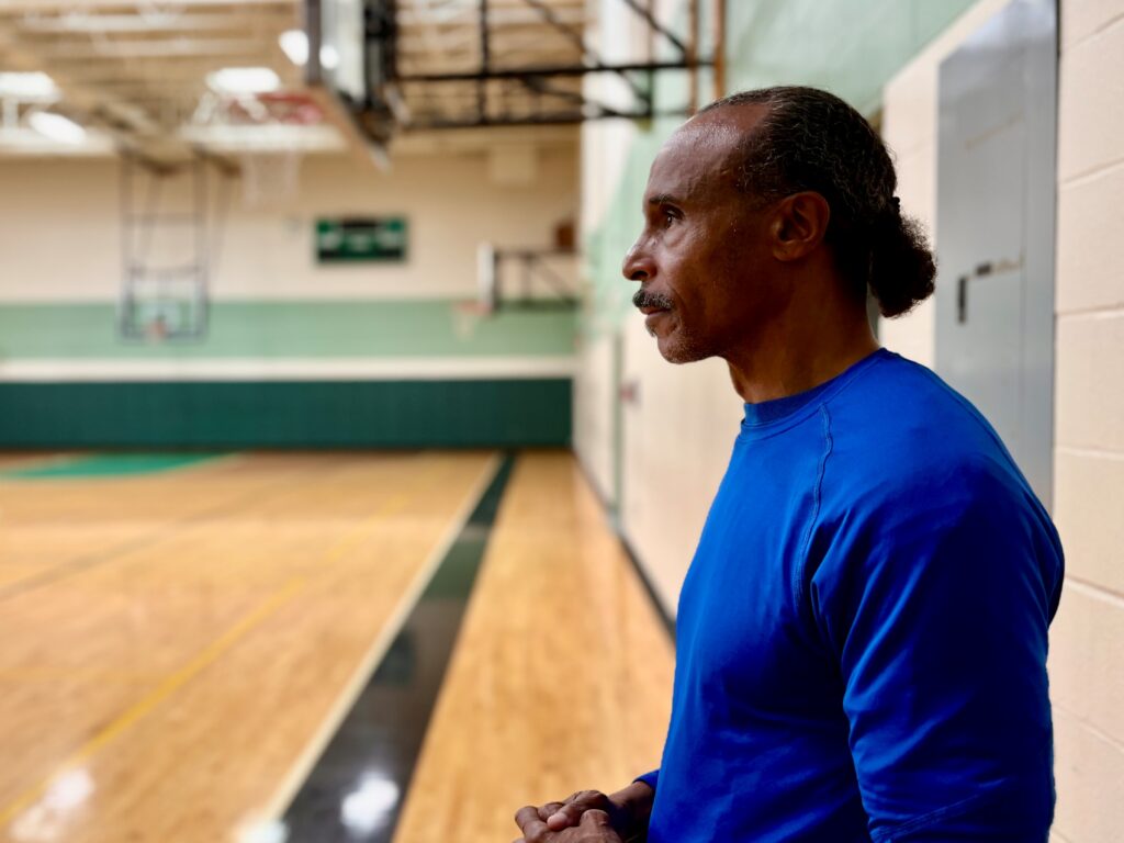 Clifford Ryan stands in a gym, looking off into the distance.
