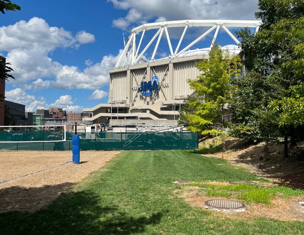 The outside of the JMA wireless dome on a sunny day. Dry, patchy grass is in the foreground. 