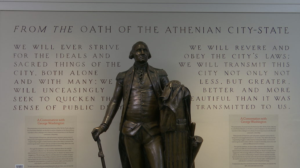 The Athenian Oath displayed on the wall, in the middle is a George Washington statue. 