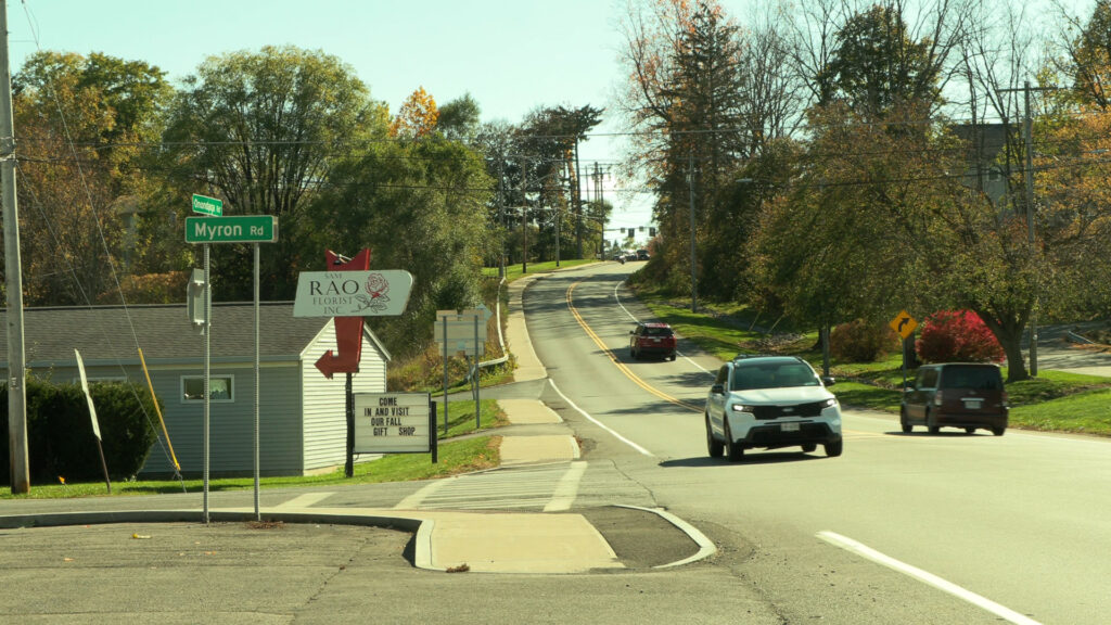 White and red cars ride in front on Onondaga Road.