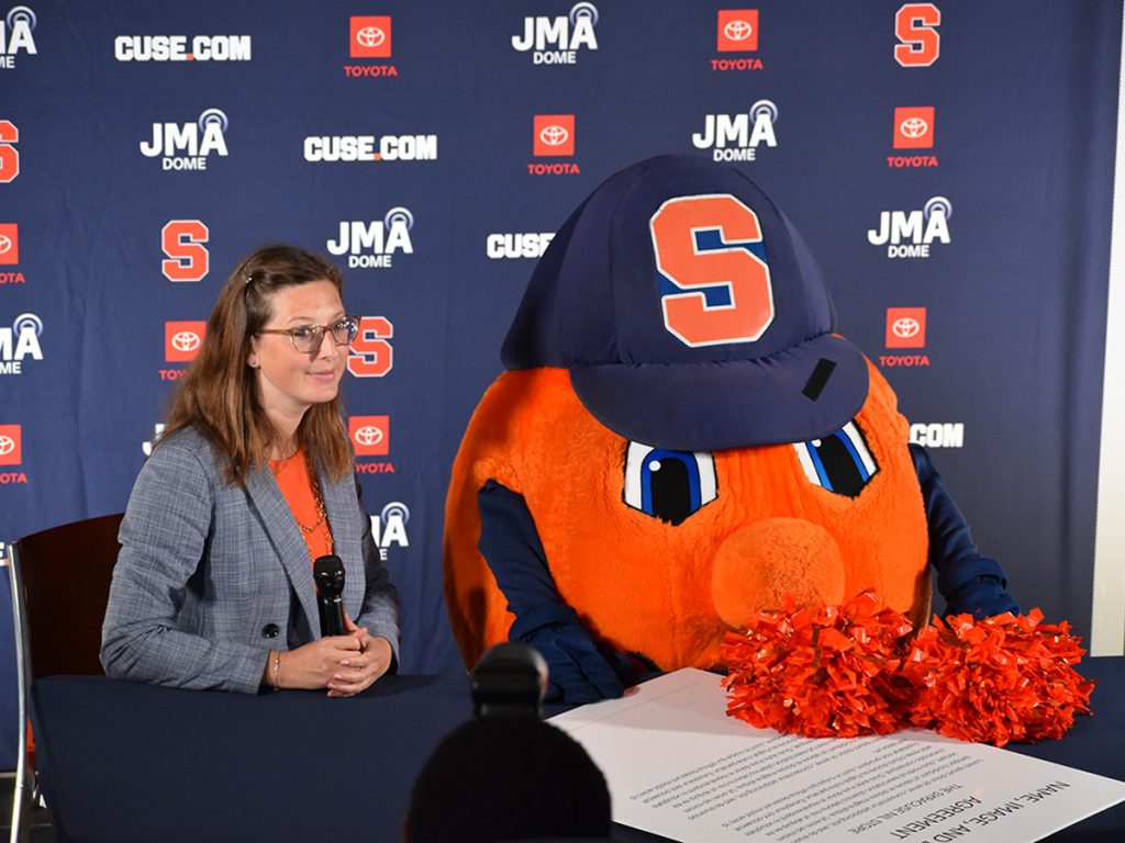 Otto the Orange and program coordinator Julie Walas sign NIL deal.