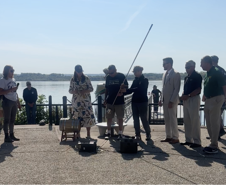 The crew of the Buffalo Maritime Center pours water from the Onondaga Lake Park into a barrel for the planting of the peace tree.
