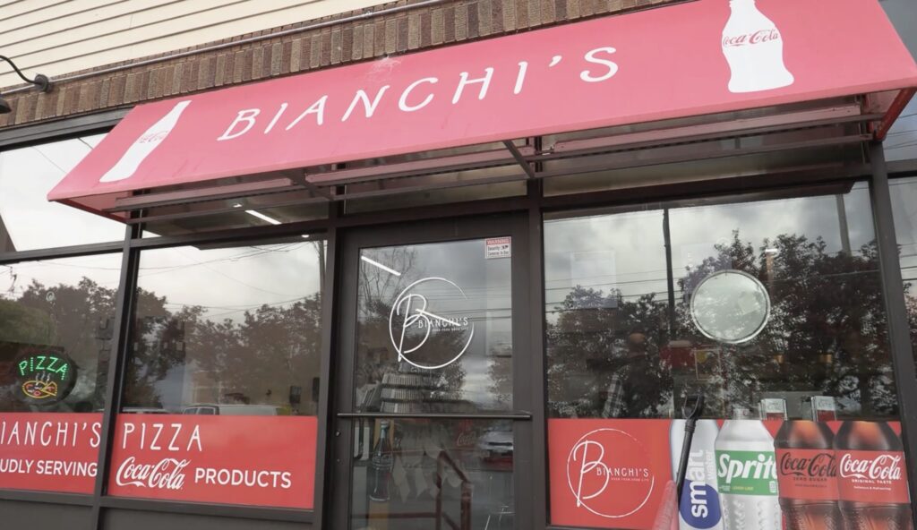 Front of pizza shop with store's logo and banner