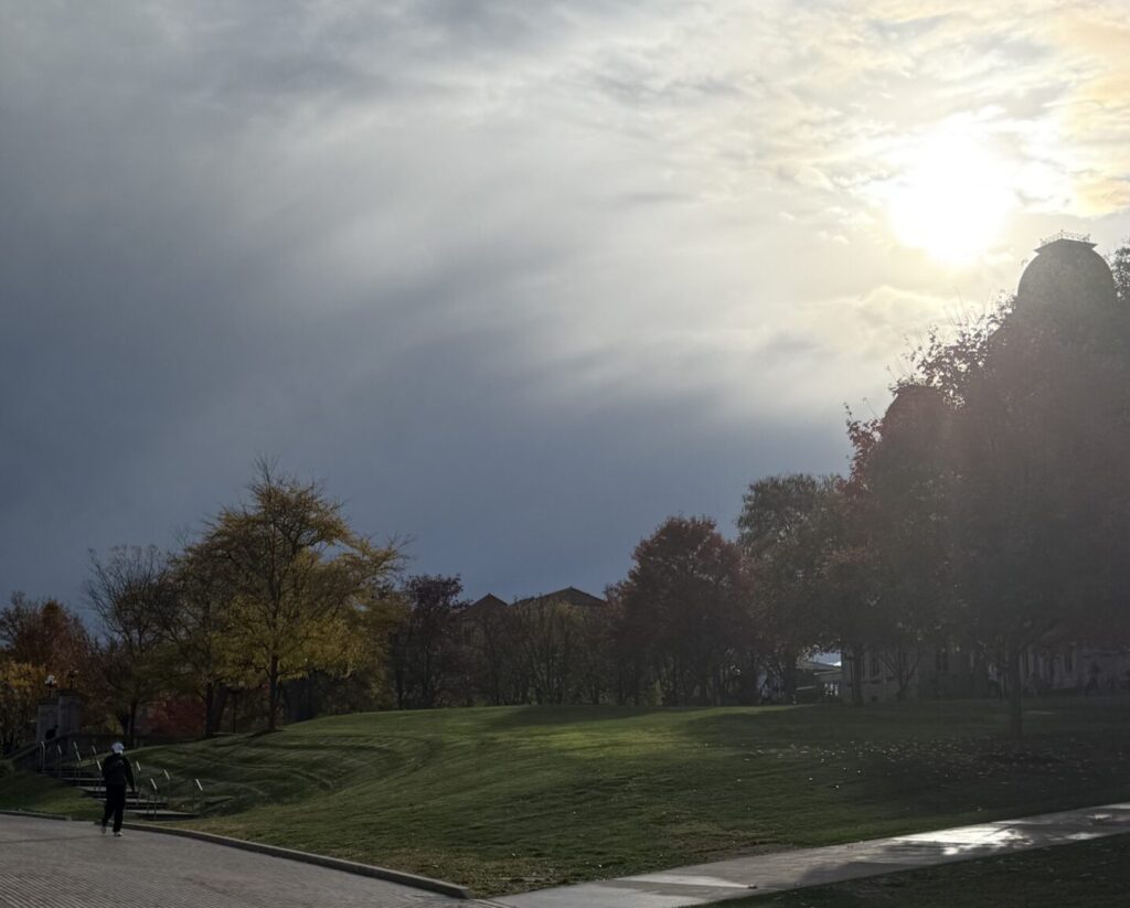 Sun shining over wet sidewalks and grass after a rainy morning in Syracuse.
