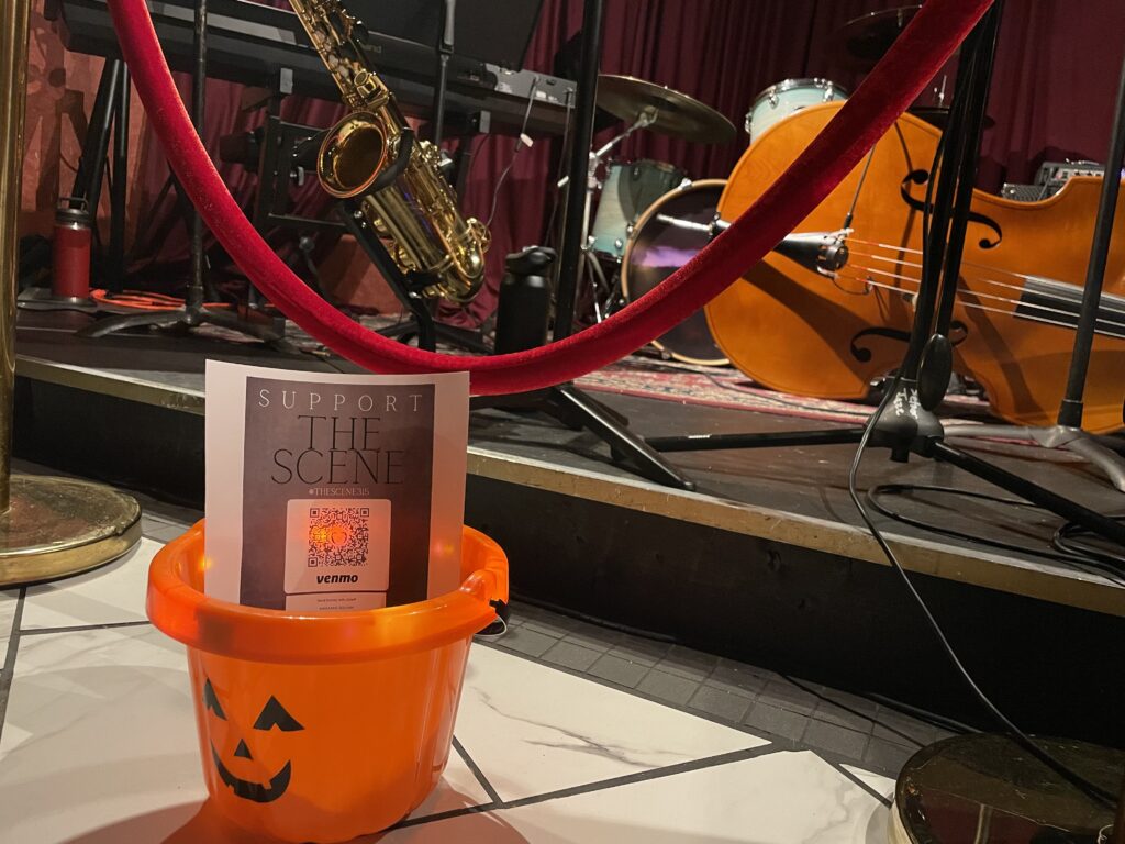 A pumpkin bucket sits in front of instruments on stage.