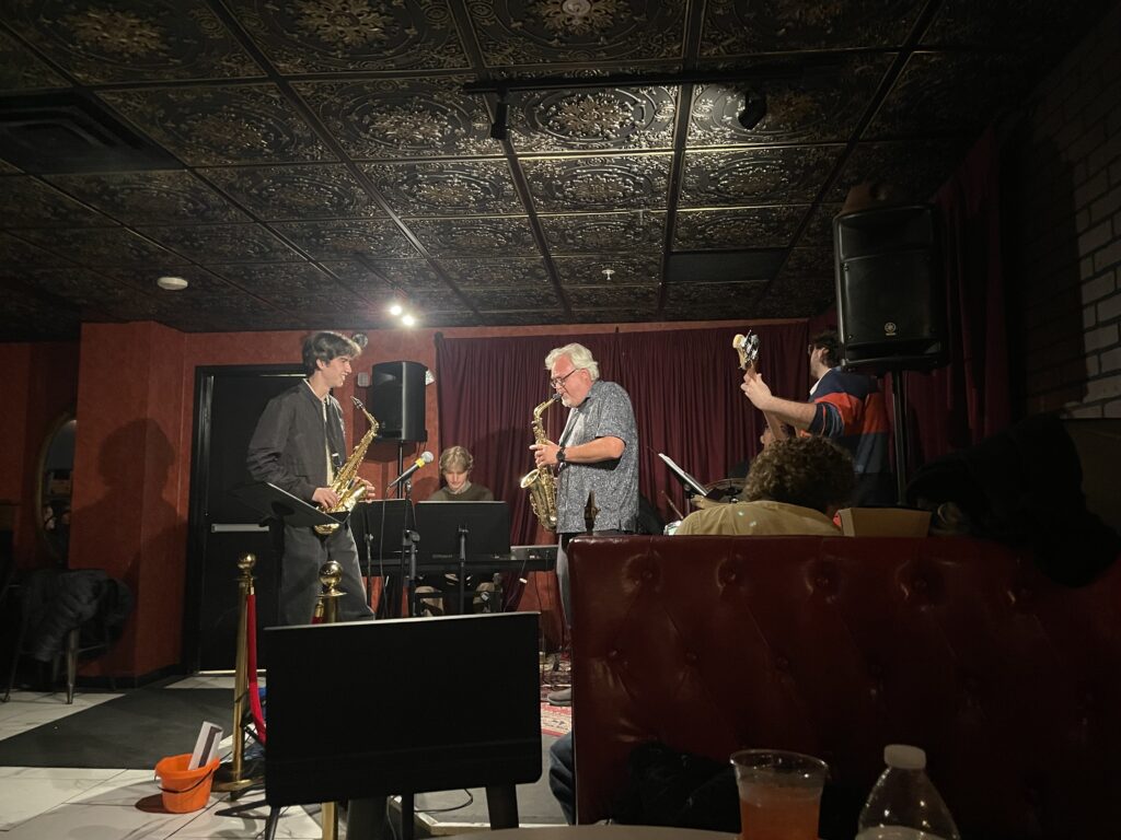 Students and community members jam out on stage with jazz instruments.