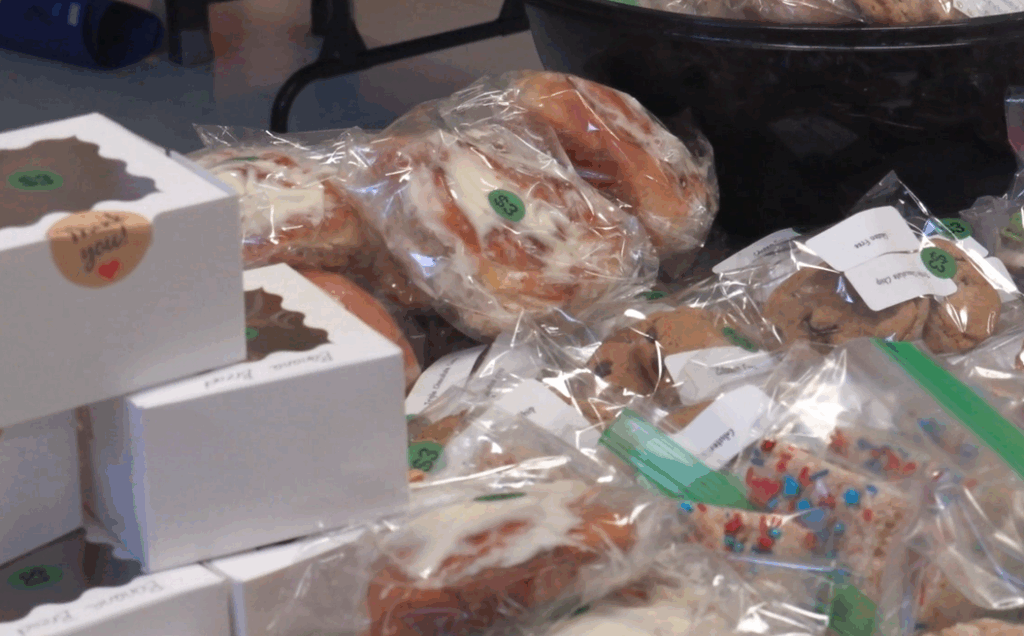 Baked goods, including banana bread, donuts and Rice Krispies treats piled on a table.