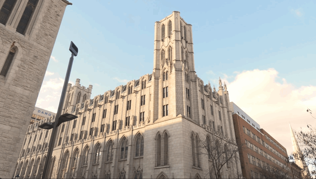 A picture of a large gothic-looking building in the middle of downtown Syracuse.