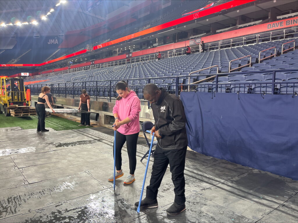 Crew members work to lay the floor for the next event at the JMA Wireless Dome.
