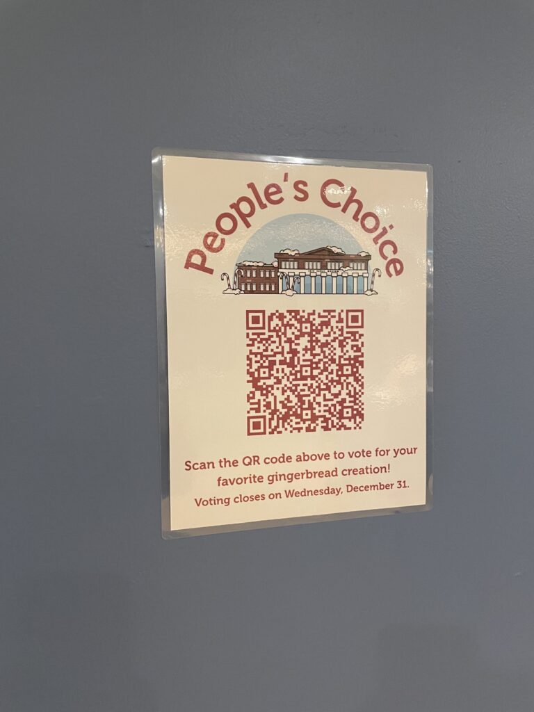 The poster in the gallery with a QR for visitors to vote on their favorite gingerbread creation.