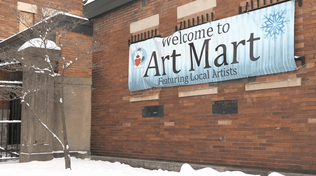 A picture of a red brick building with a sign advertising the downtown Art Mart in Syracuse.