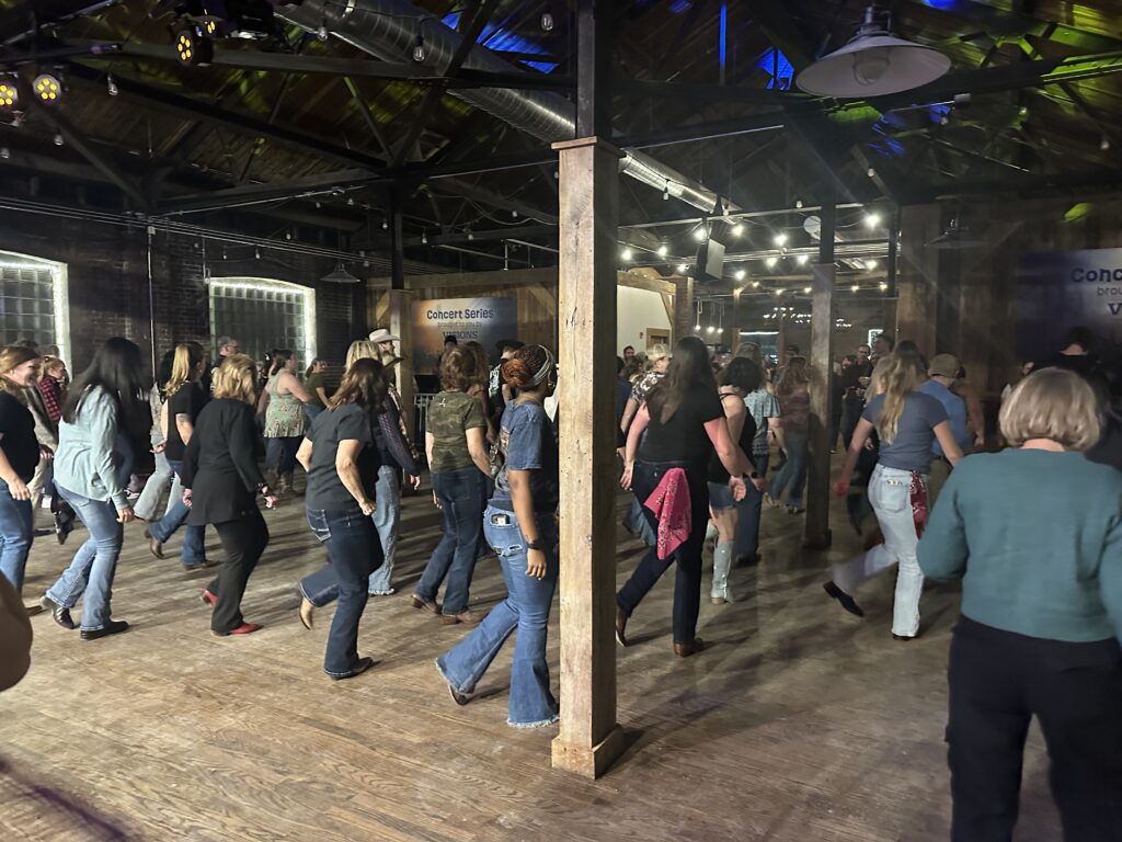 People line dance together inside Middle Ages Brewery during a Boots in the Brewery event.