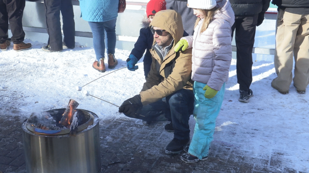 A family roasts marshmallows at the 2026 Syracuse Pond Hockey Classic.