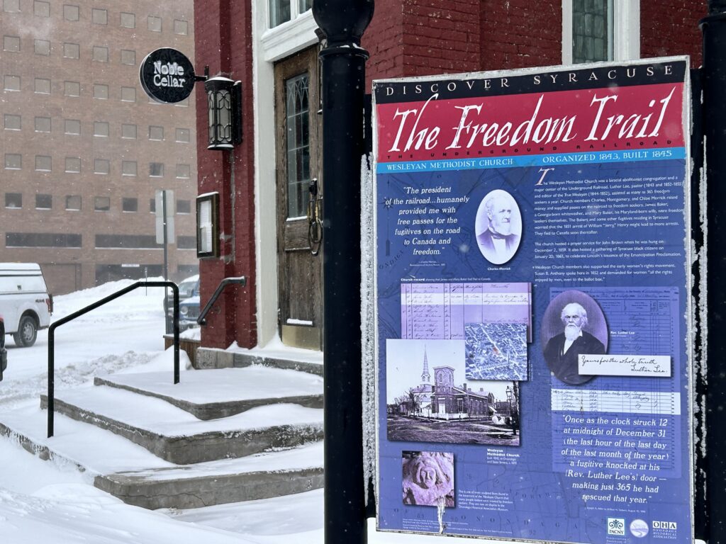 The Freedom Trail historical marker outside Noble Cellars restaurant. The marker highlights the building’s role in providing refuge to freedom seekers and invites visitors to explore the history of Syracuse’s involvement in the Underground Railroad. ©Marisa Nuñez