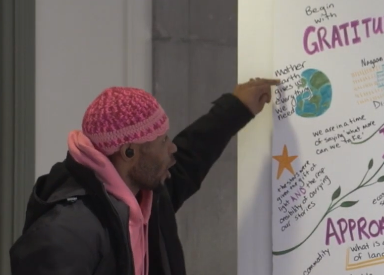 Man pointing at an image that reads "Mother Earth gives us everything we need."