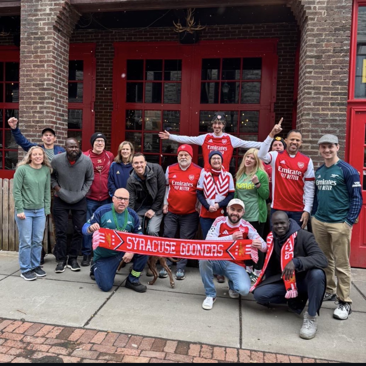 Fans of the soccer team, Arsenal, gather outside of a bar in Syracuse in merch and with a scarf
