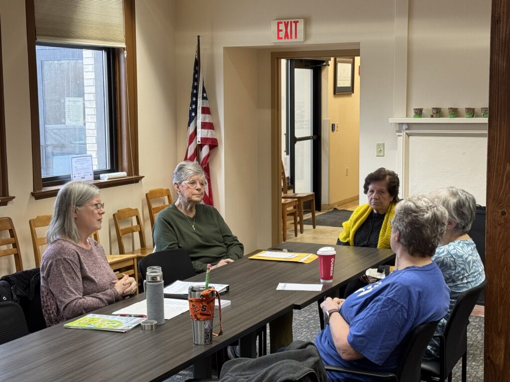 5 women sitting at a table talking to each other
