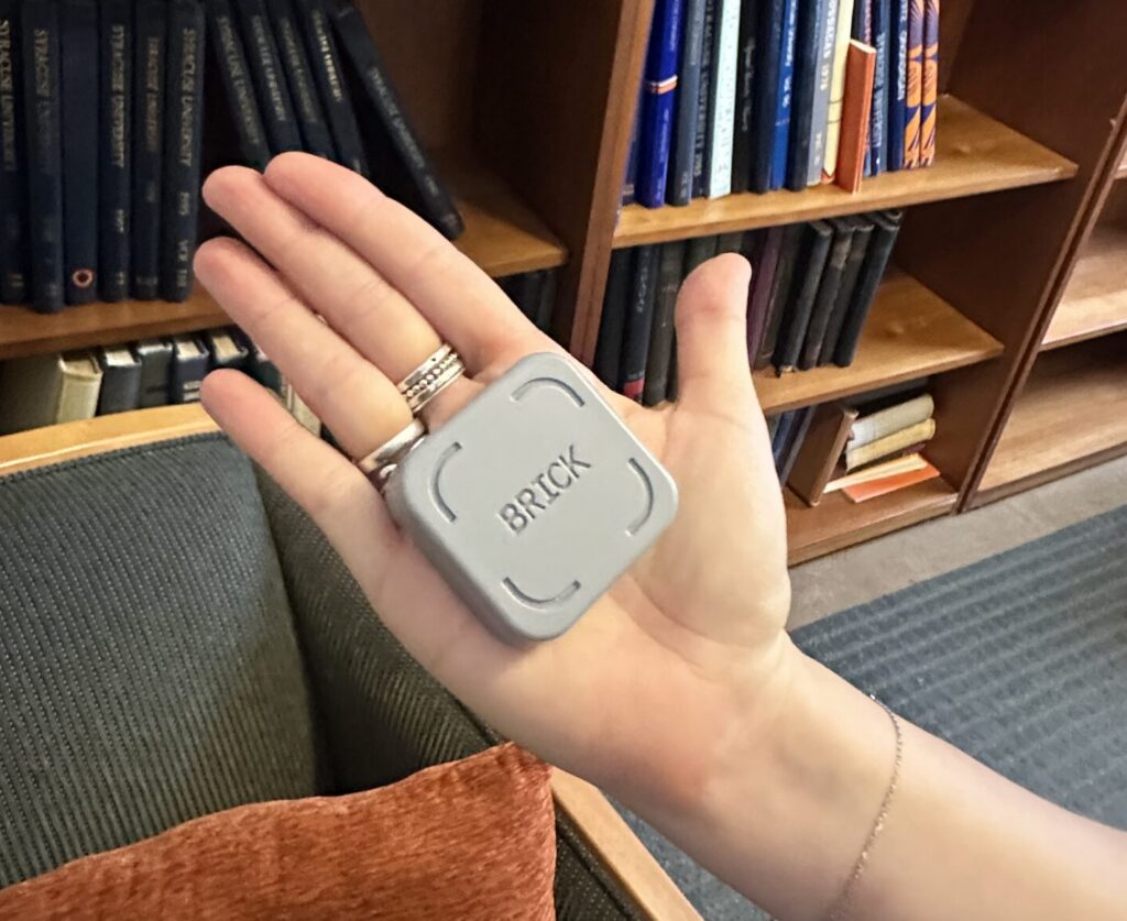 A small gray box that says 'brick' in the palm of someone's hand