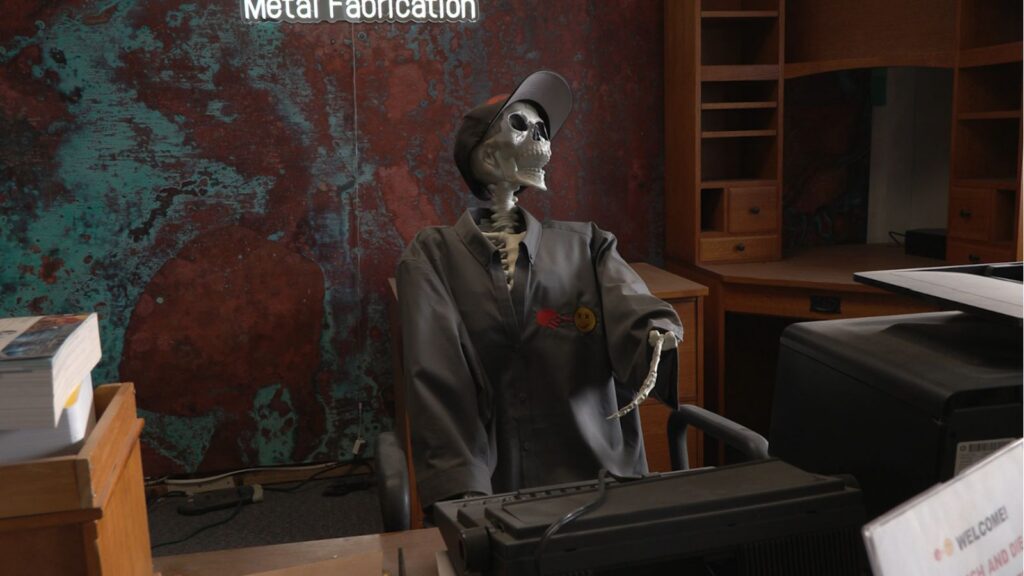 Metal skeleton sitting behind receptionist desk at a metal fabrication company.