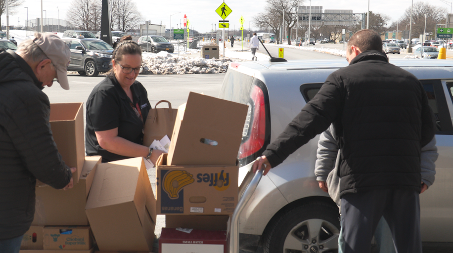 People lifting boxes of food out of car