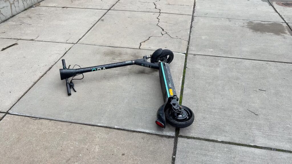 A scooter lying on the sidewalk.